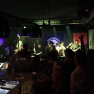 A live jazz session at Jazzbina. The room is full and a man sings.